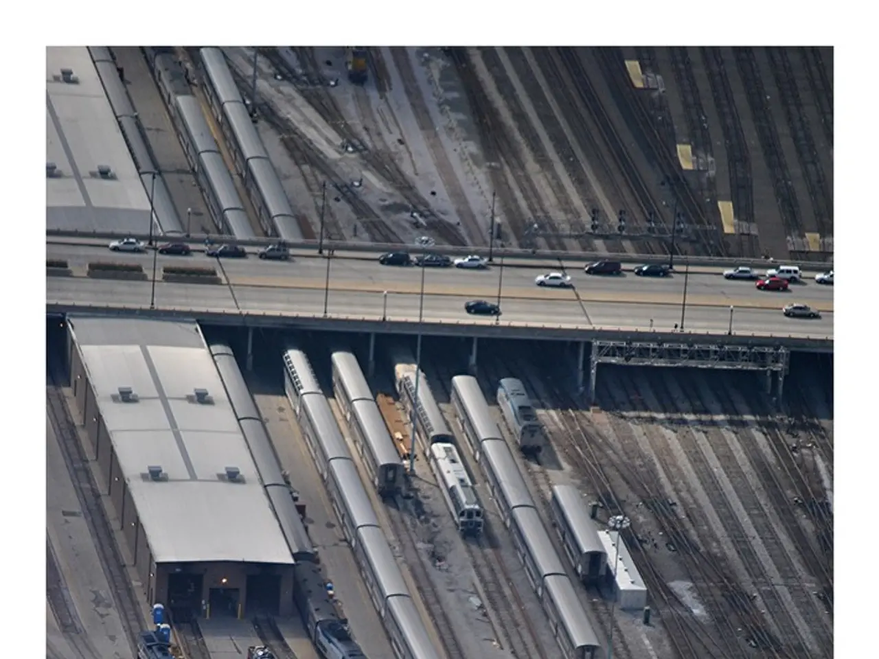 In this image we can see few vehicles on the bridge, there are few trains on the railway tracks...