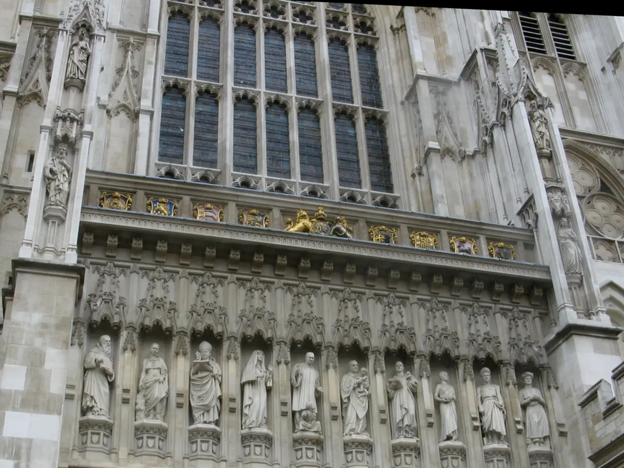 In the image there is a building with walls, glass windows, pillars, sculptures, arch and some...