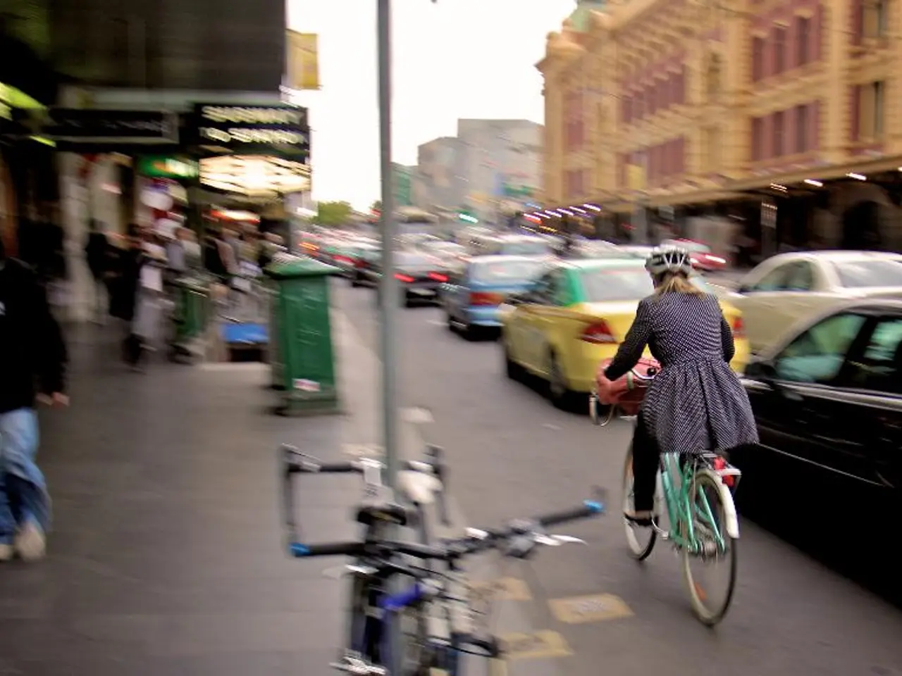 This is a street view. A girl wearing a helmet is riding a cycle on the road. Also there are many...