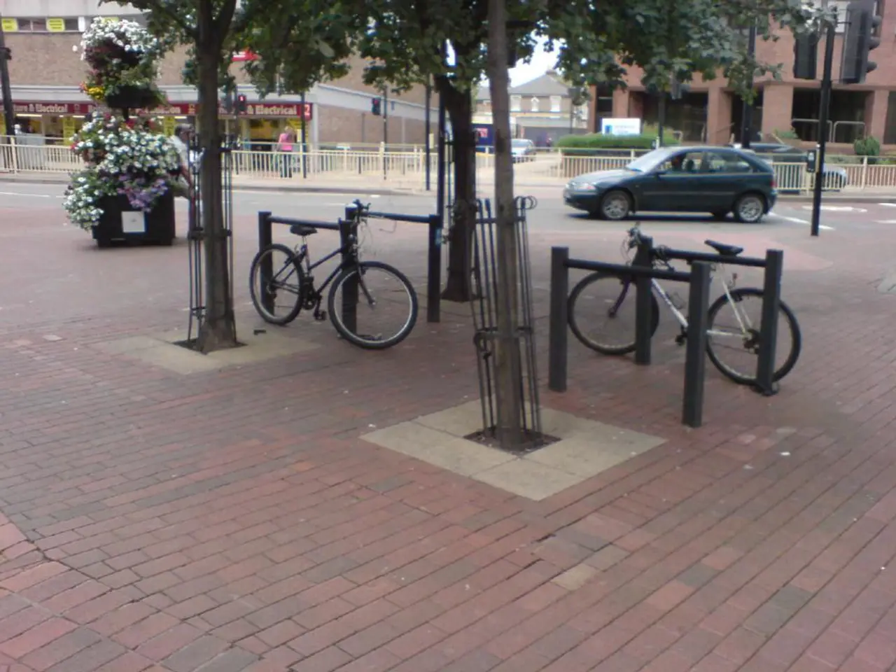 As we can see in the image there are bicycles, trees, fence, car and buildings.