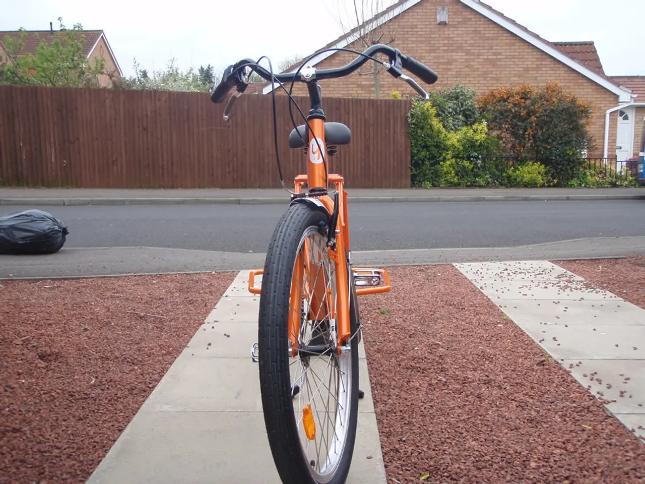 In the center of the image, we can see a bicycle on the side way and there is a bag on the road. In...