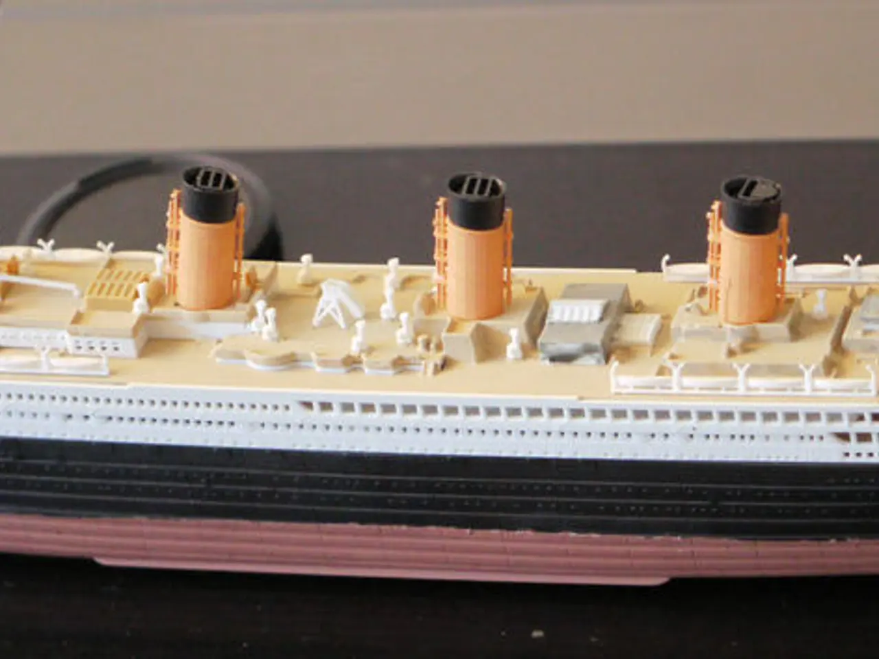 In this image I can see a toy ship in the front. I can see colour of the ship is cream, white,...