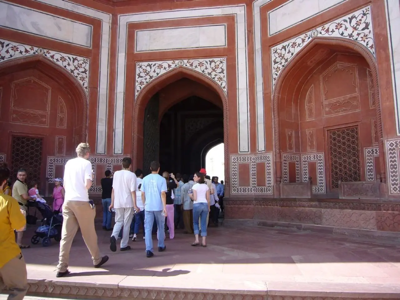 In the foreground of the picture there are people walking and there is floor. In the center of the...