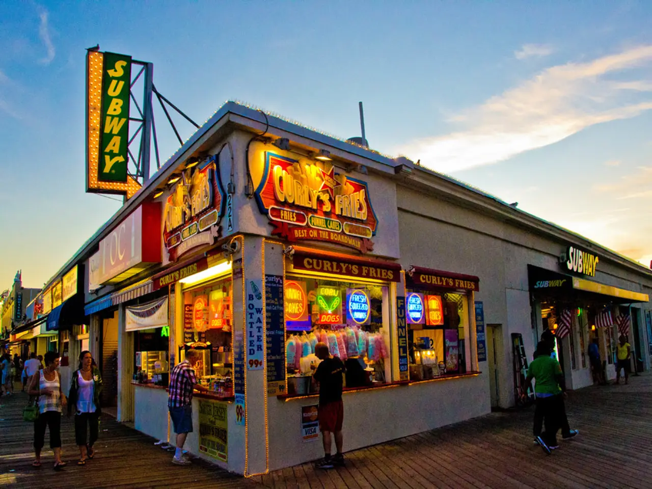 In the center of the image there are stores. At the bottom of the image there is a road. There are...