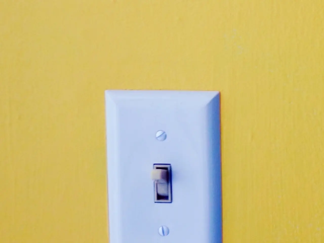 In the image we can see there is a white colour switch on the wall and the wall is in yellow...