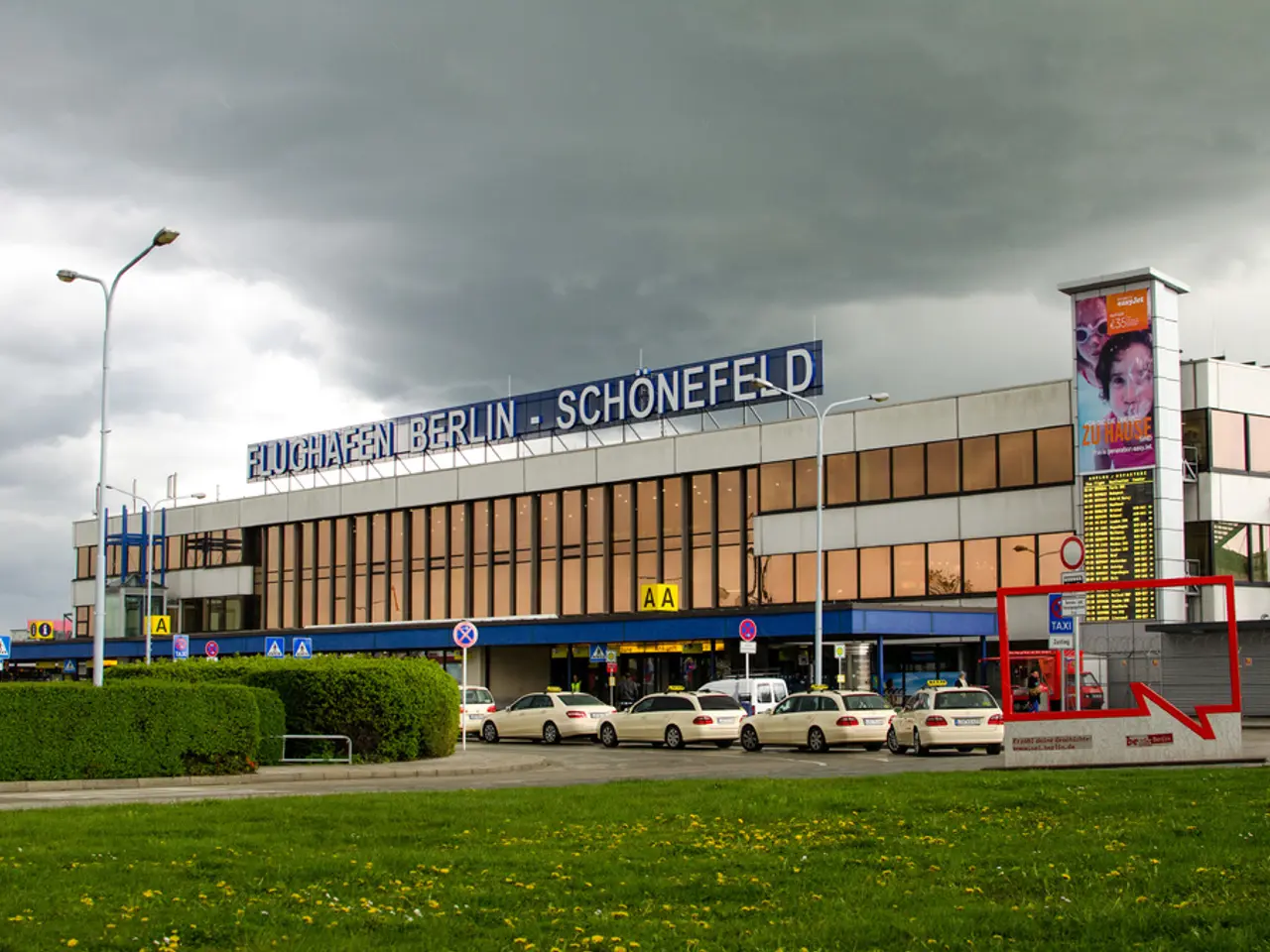 In this image we can see the grass, shrubs, vehicles parked here, caution boards, light poles,...