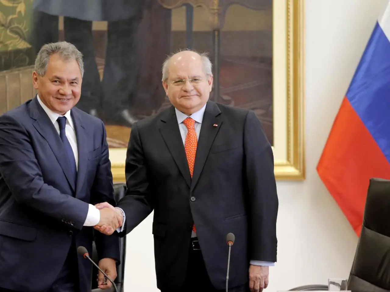 In this picture, there are two men wearing blazers. Both of them are shaking hands. Before the,...