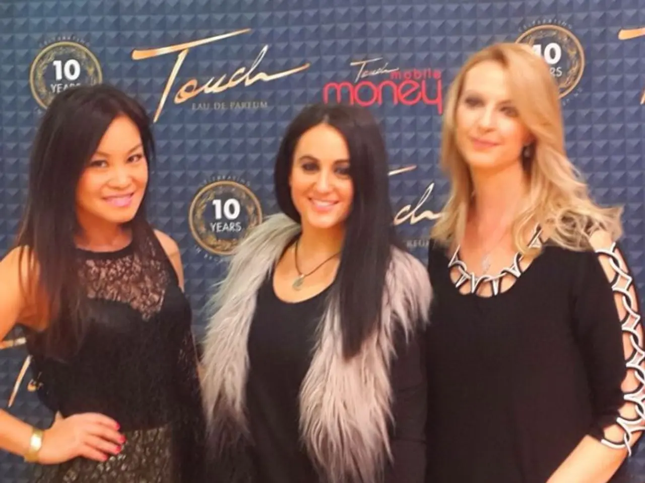 The picture consists of three women wearing black dress. In the background there is a banner.