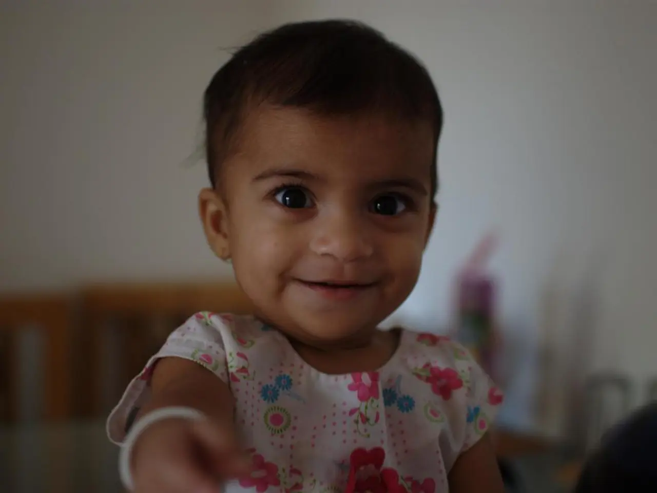In this image, I can see a baby girl smiling. The background looks blurry.