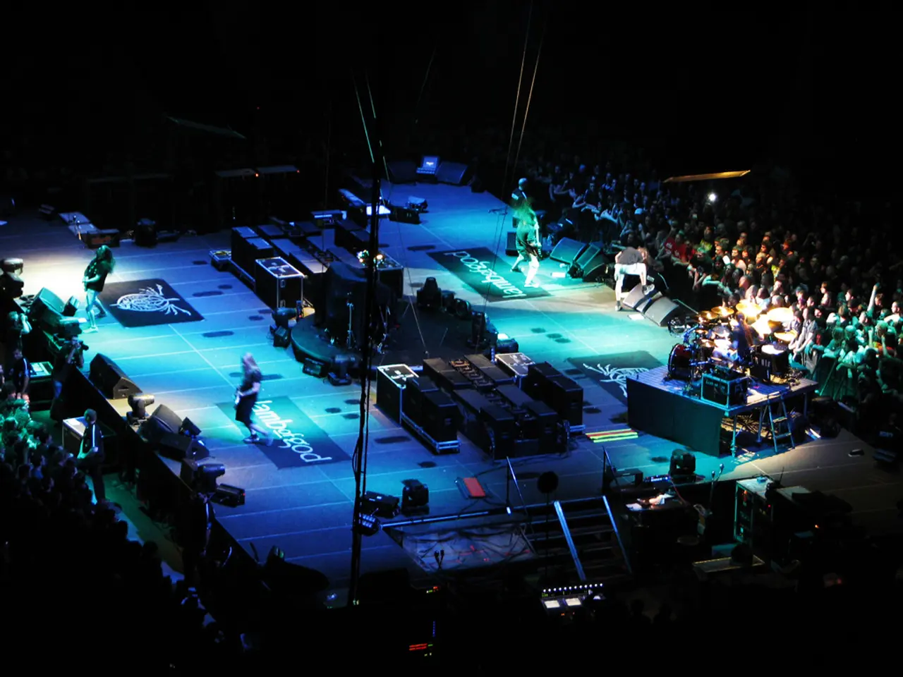 This image consists of few people performing on the dais. On the days, we can see many boxes and...