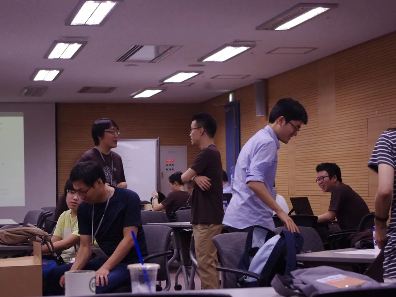 It looks like a classroom, there are many tables and chairs and on the tables there are few laptops...