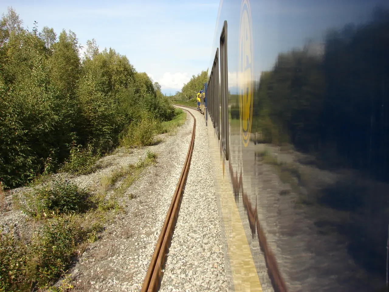 This image is clicked outside. There is a train on the right side. There are trees on the left...
