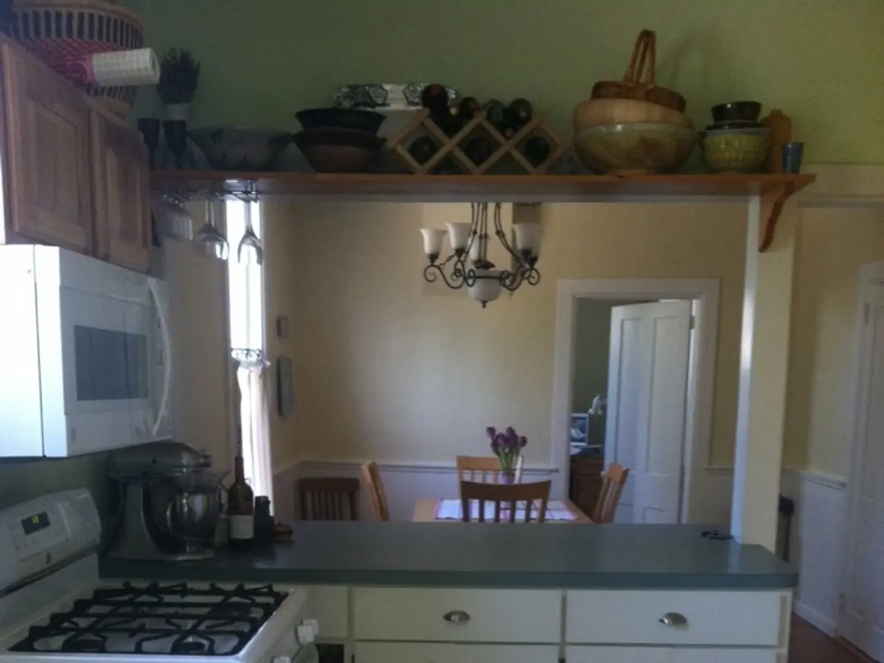 This is a image of the kitchen on which we can see there is a table, stove, dining table and some...