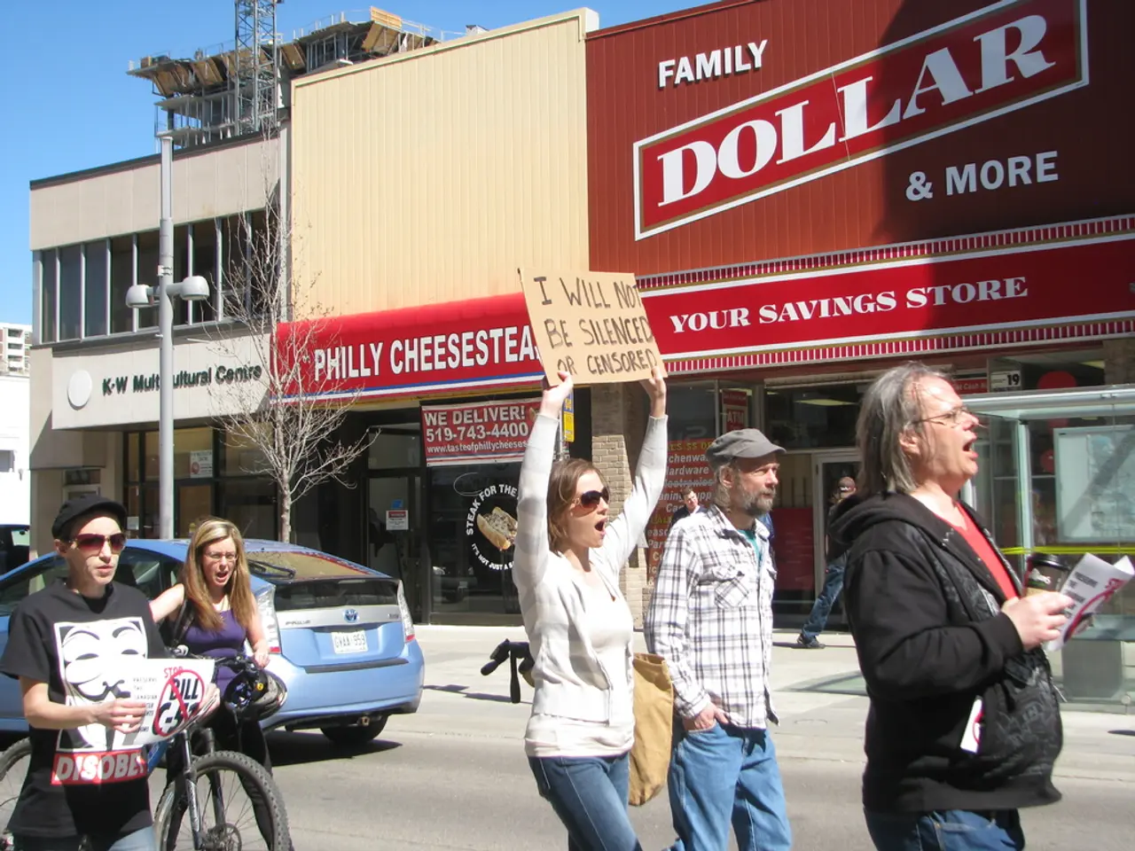 In this image we can see people are protesting on the road. In the background, we can see...