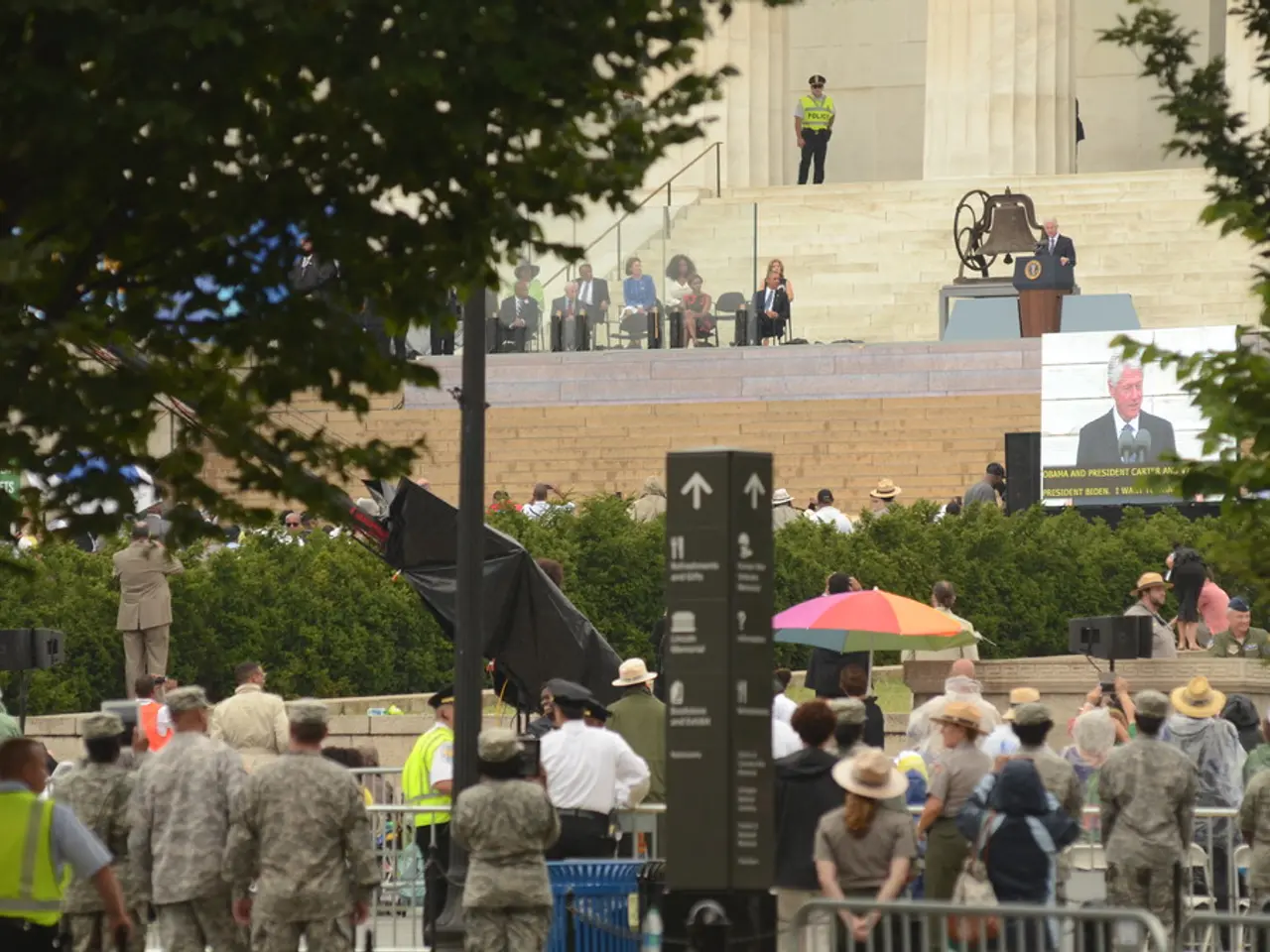 In this image there are few army men and civilians hearing a speech delivered by the president, in...