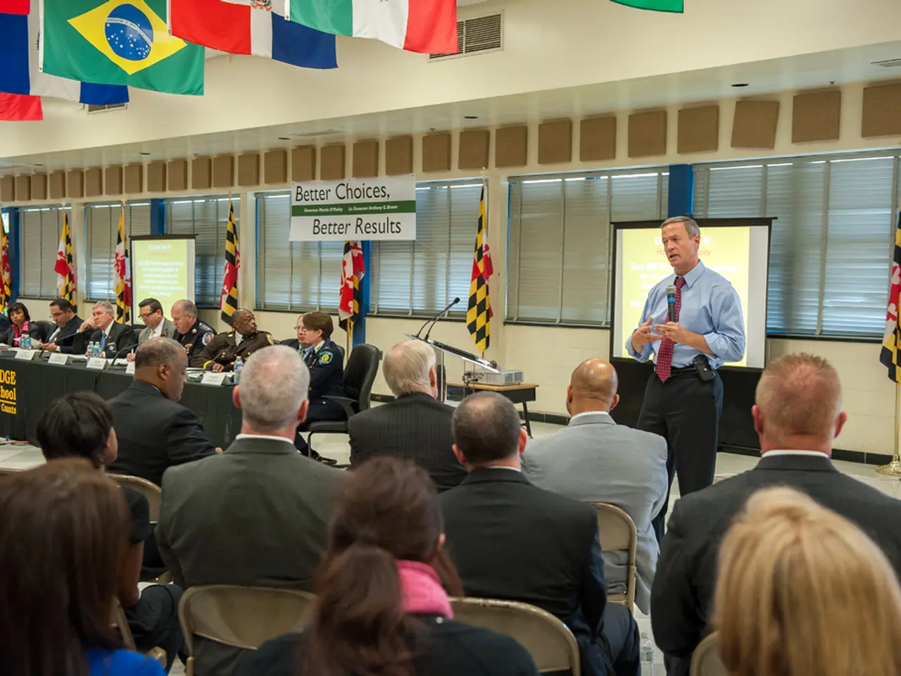 Here in this picture in the front we can see number of people sitting on chairs present on the...