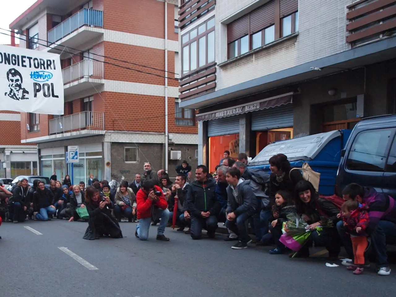 This image consists of many people on the road. In the front, there are two persons holding...