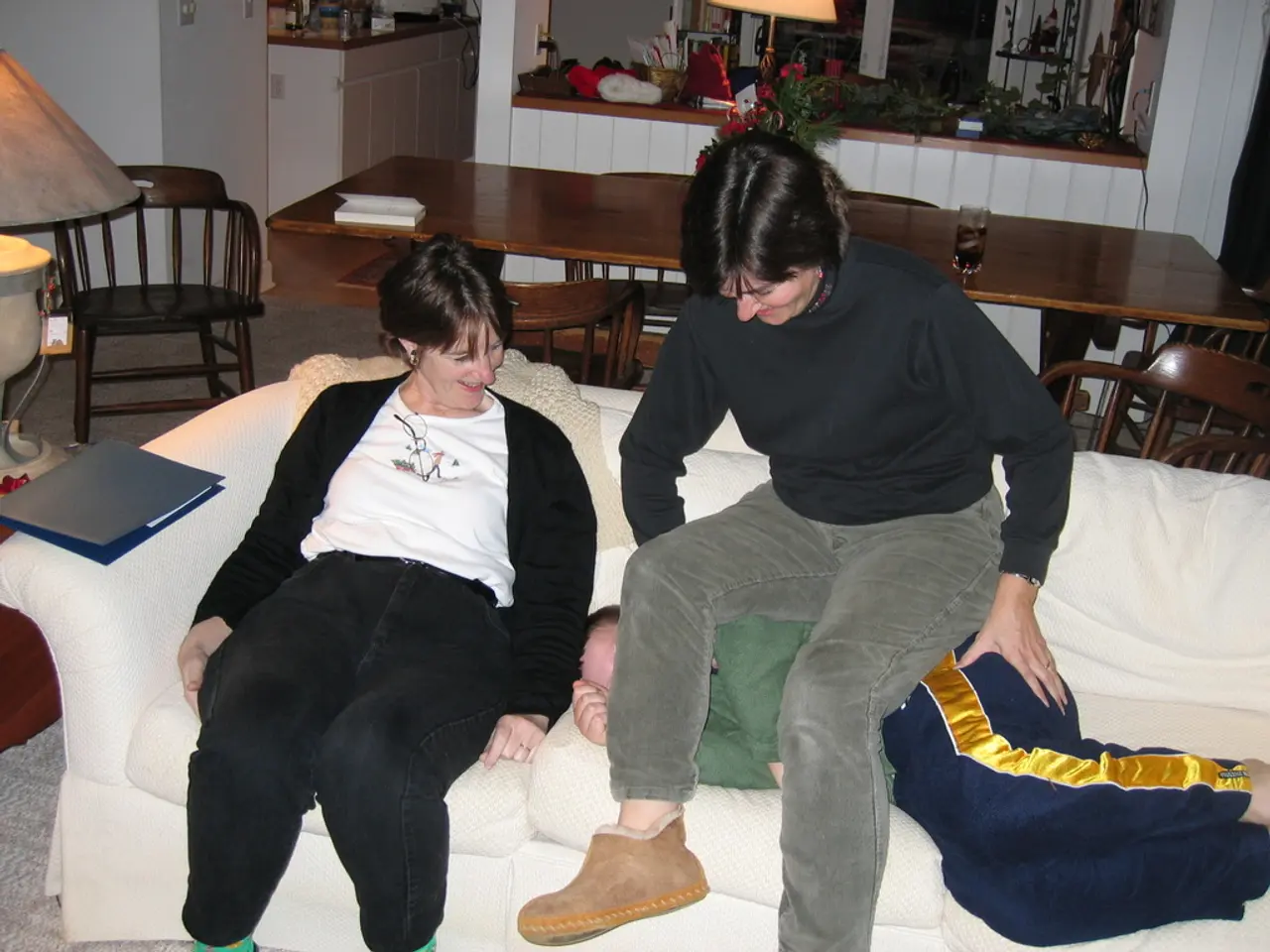 There are two persons laughing. One of them is sitting on a sofa, another one is sitting on a...