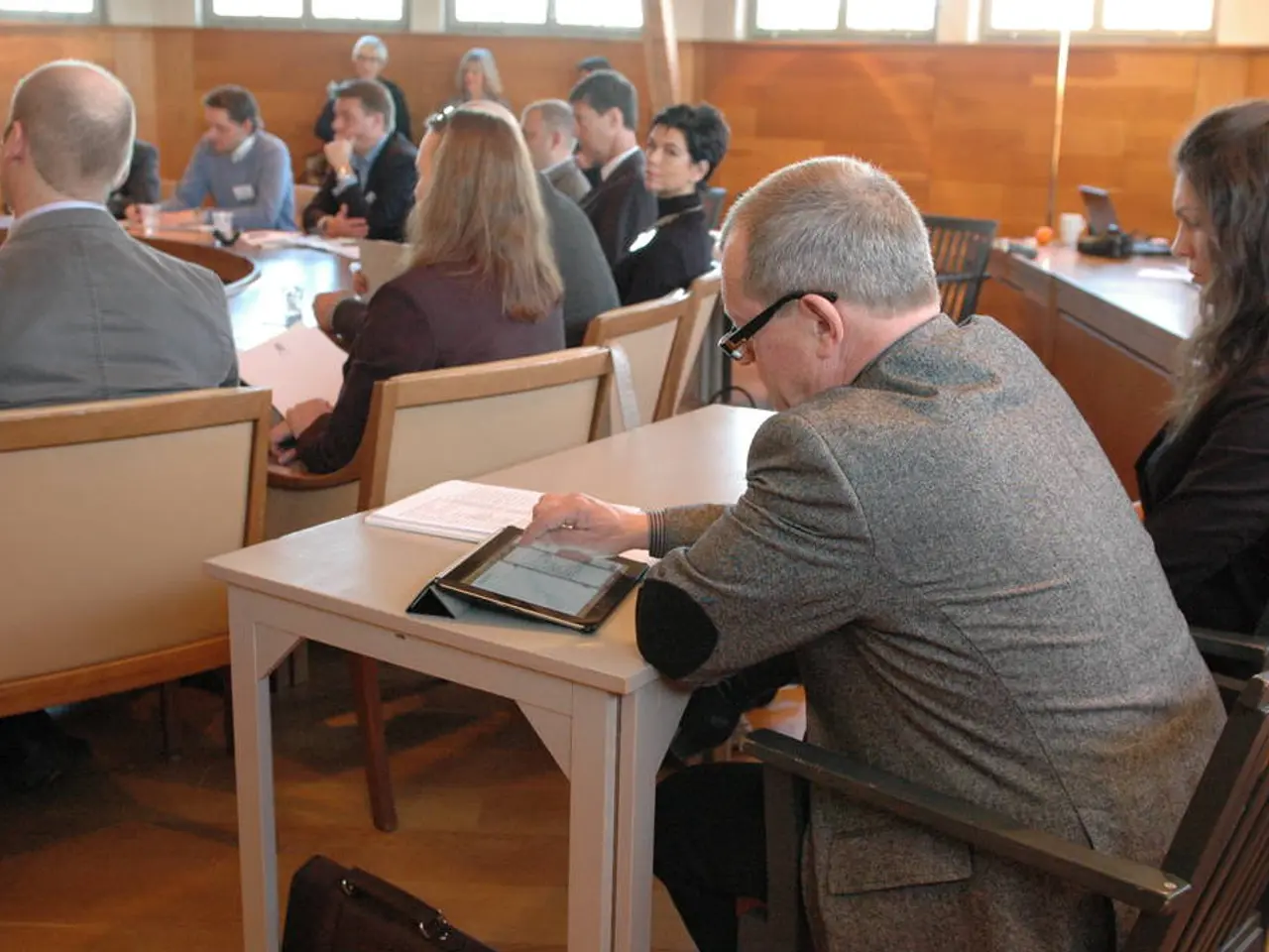 Here we have 2 people who are sitting on black chairs and this man is having tablet and lady is...