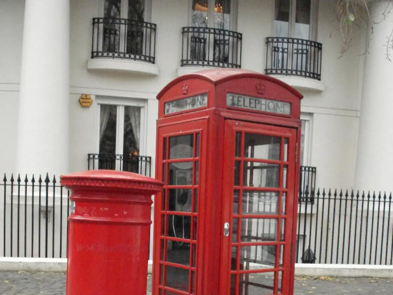 This image consists of a post box and a telephone booth in red color. At the bottom, there is a...