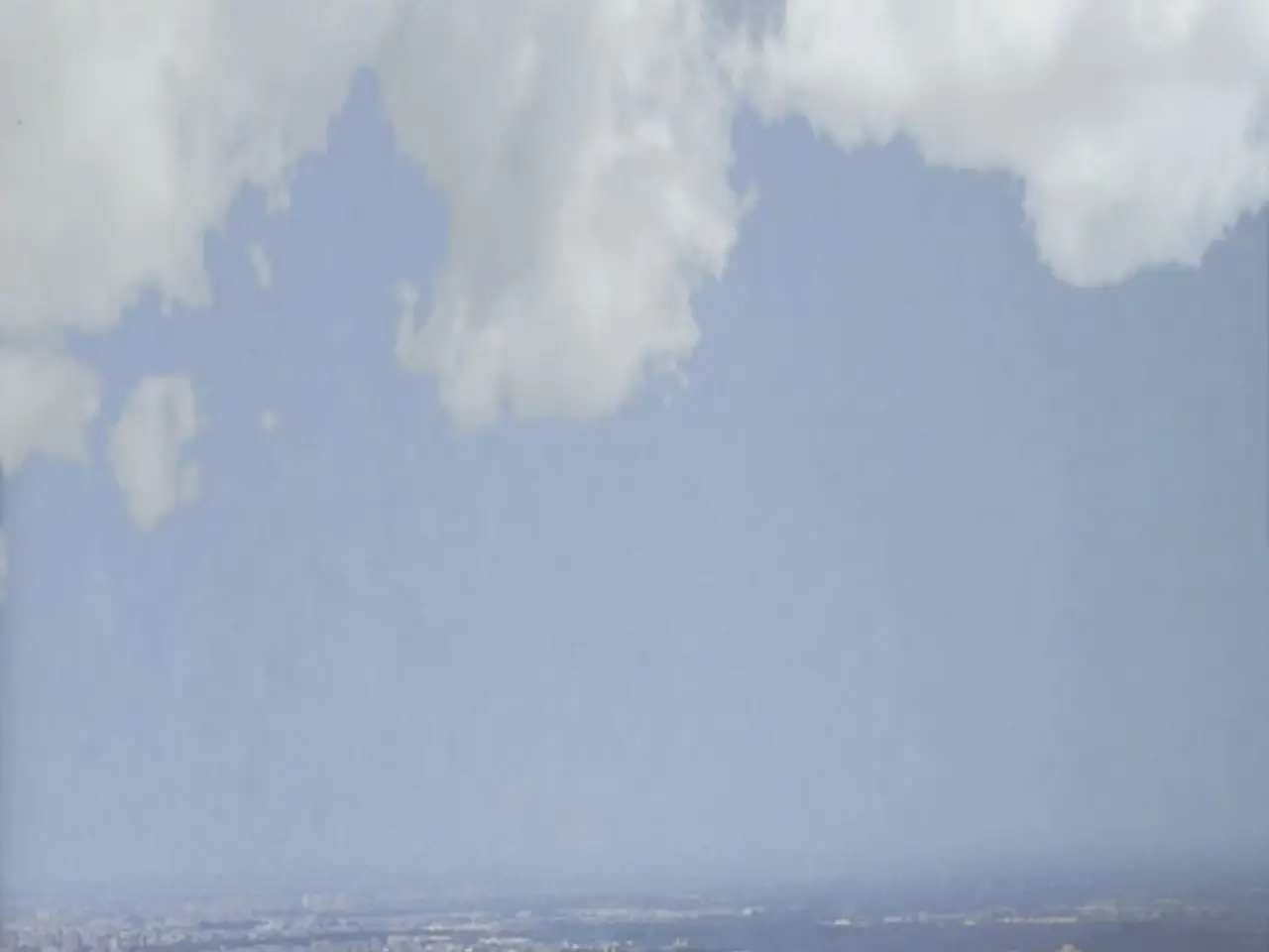 In this picture I can see the city. At the bottom I can see the skyscrapers, buildings and sheds....