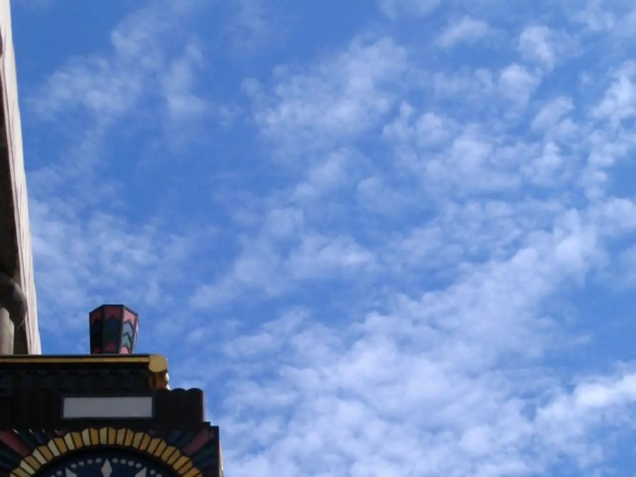 In the picture I can see a clock is attached to an object. In the background I can see the sky.