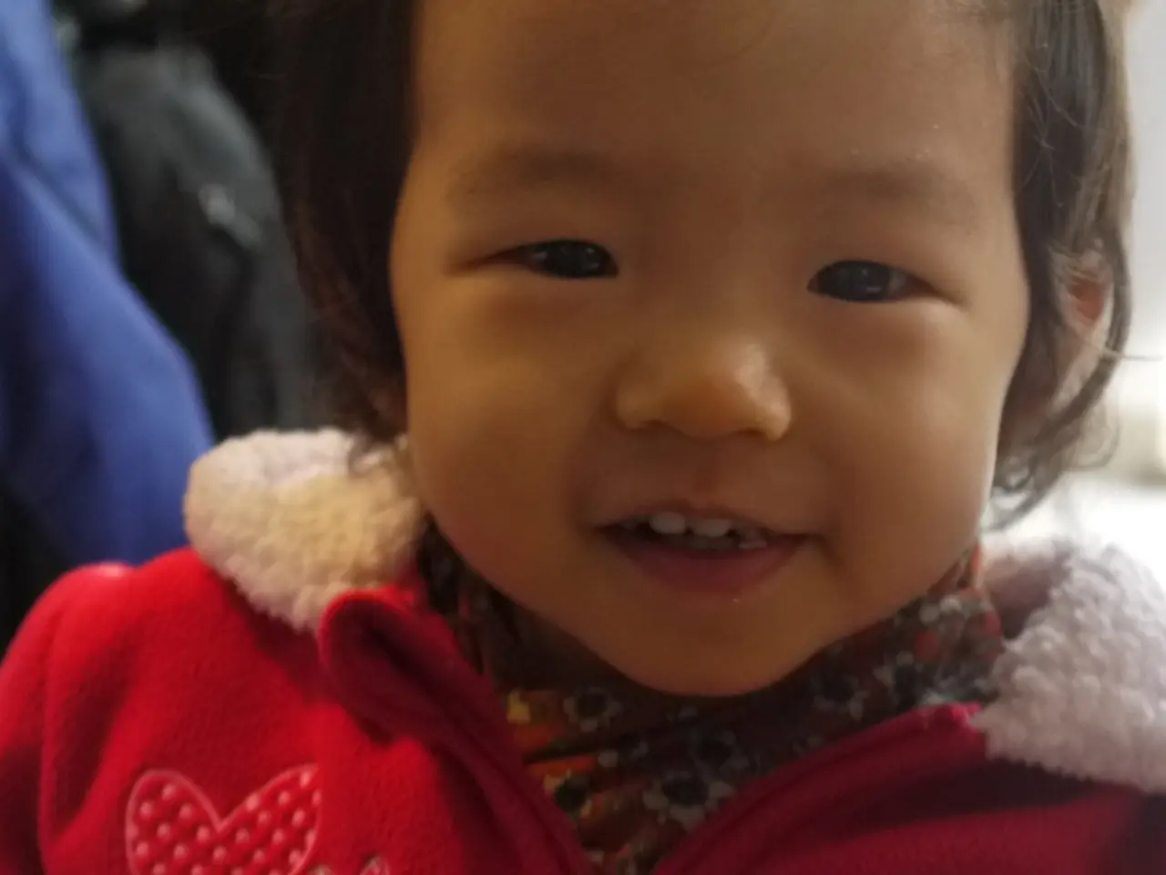 In this image in the foreground there is one baby smiling, and in the background there are some...