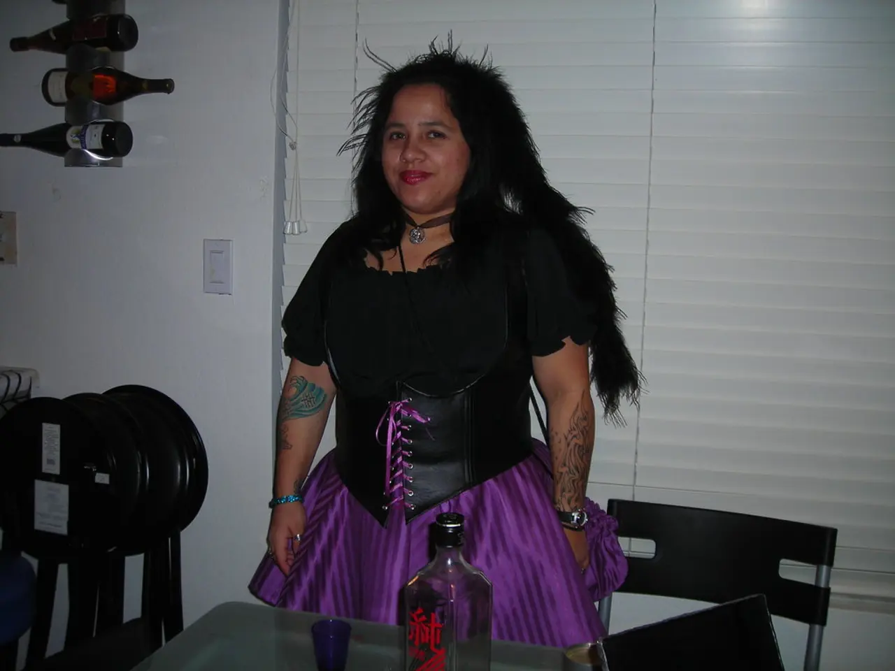 In the image a woman is wearing purple and black dress she is posing for a photo to her left there...