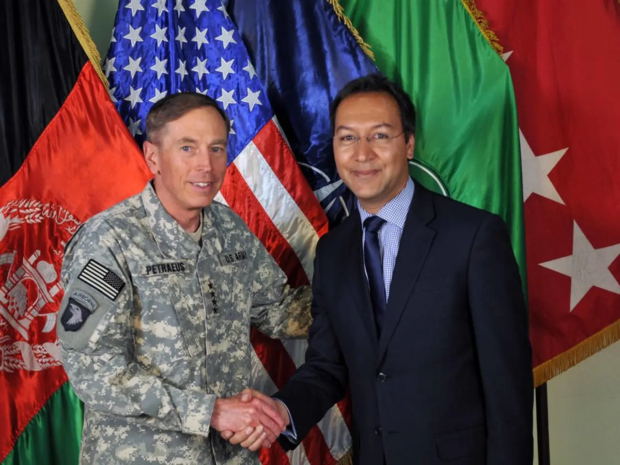 In the middle of the image two persons are standing and smiling. Behind them there are some flags....