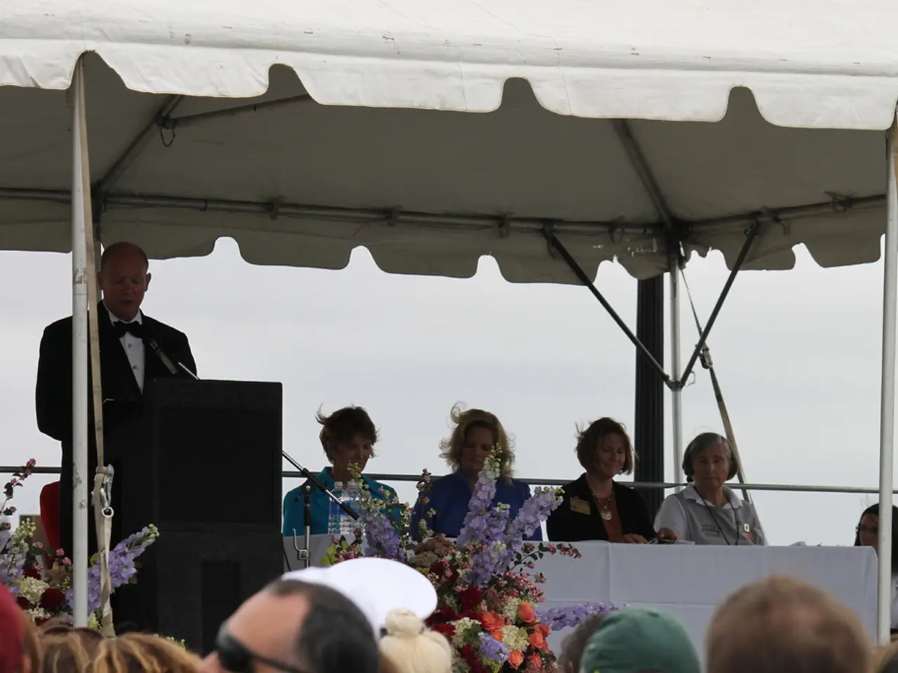 In this picture I can see group of people, there are flowers, group of people sitting , there are...