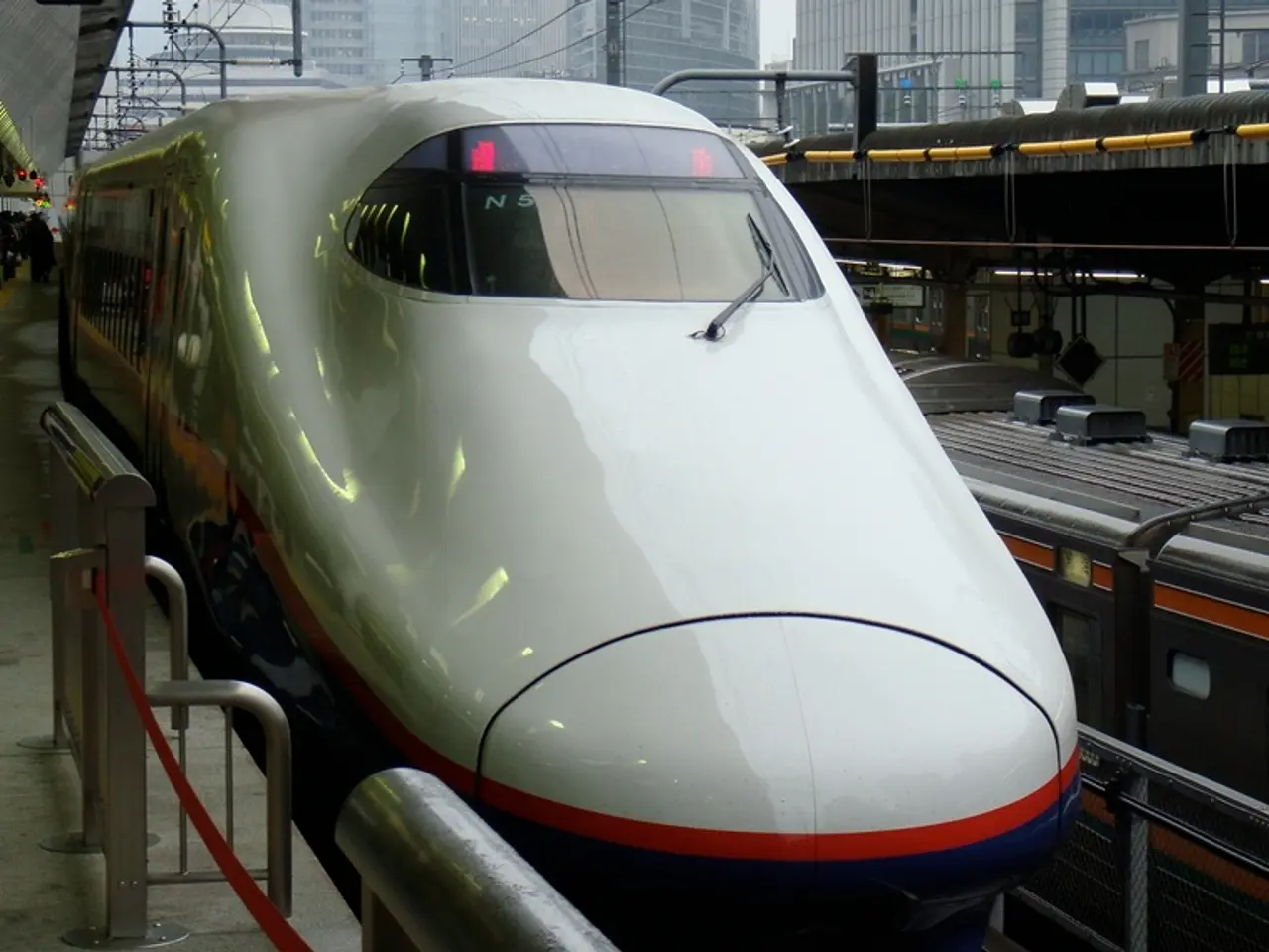 In this image there is a train on the rail track. Few persons are standing on the platform having...