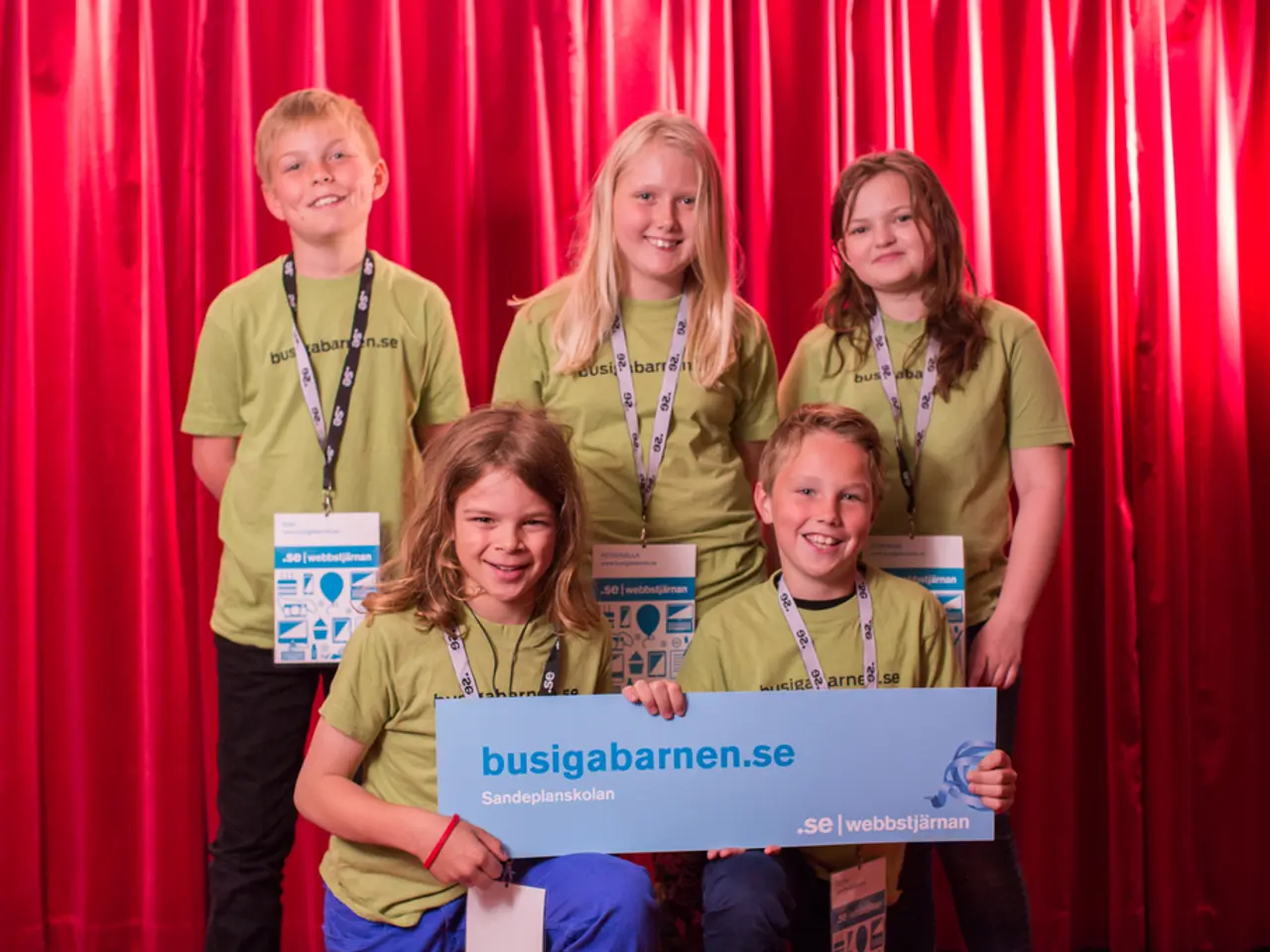 In this image we can see group of children wearing id cards. A boy and a girl are holding a board...