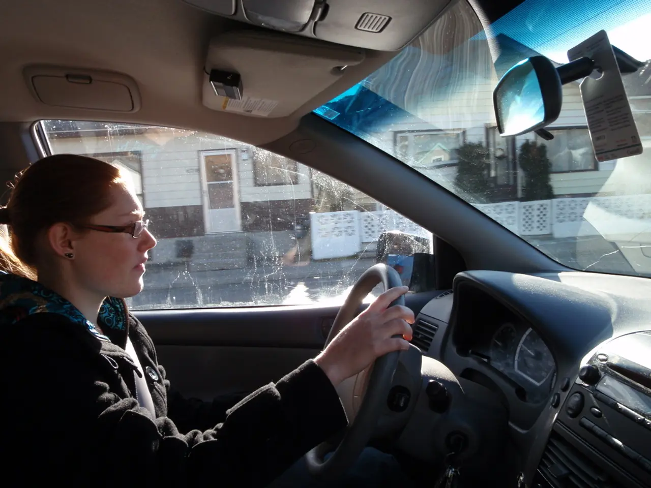 The image is taken in the car. In the car there is a lady who is driving the car.