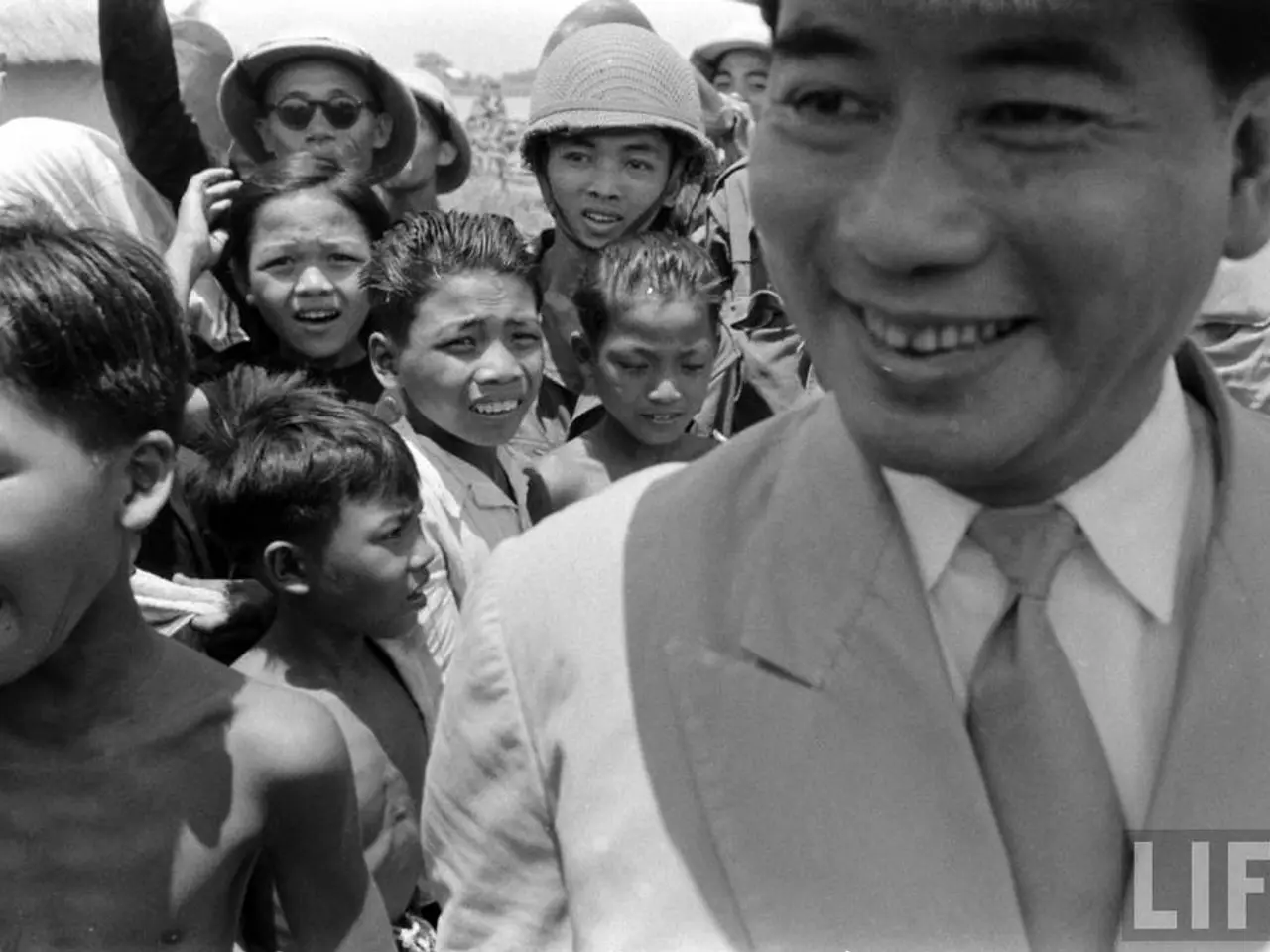 In this black and white image, we can see some kids. There is a person on the right side of the...