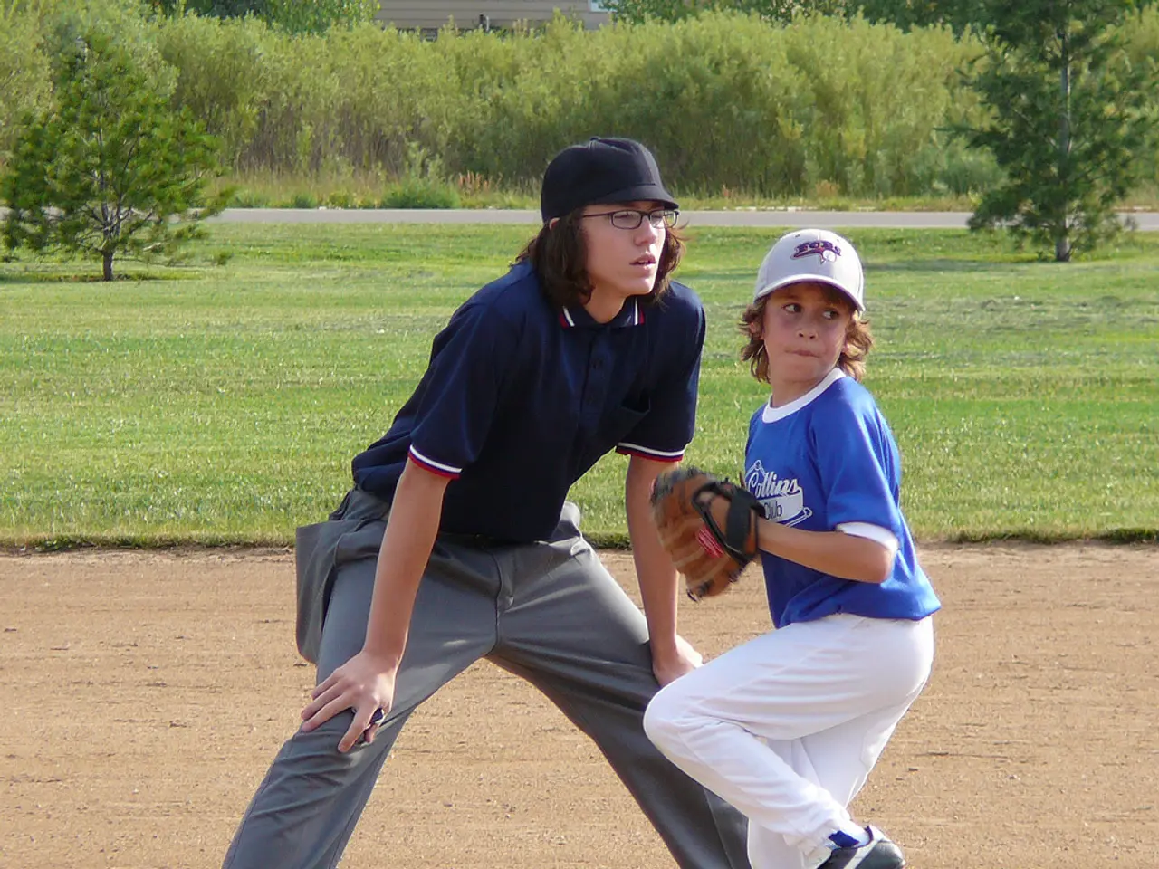 In this image there is a mud road at the bottom. There are two people in the foreground. There is a...