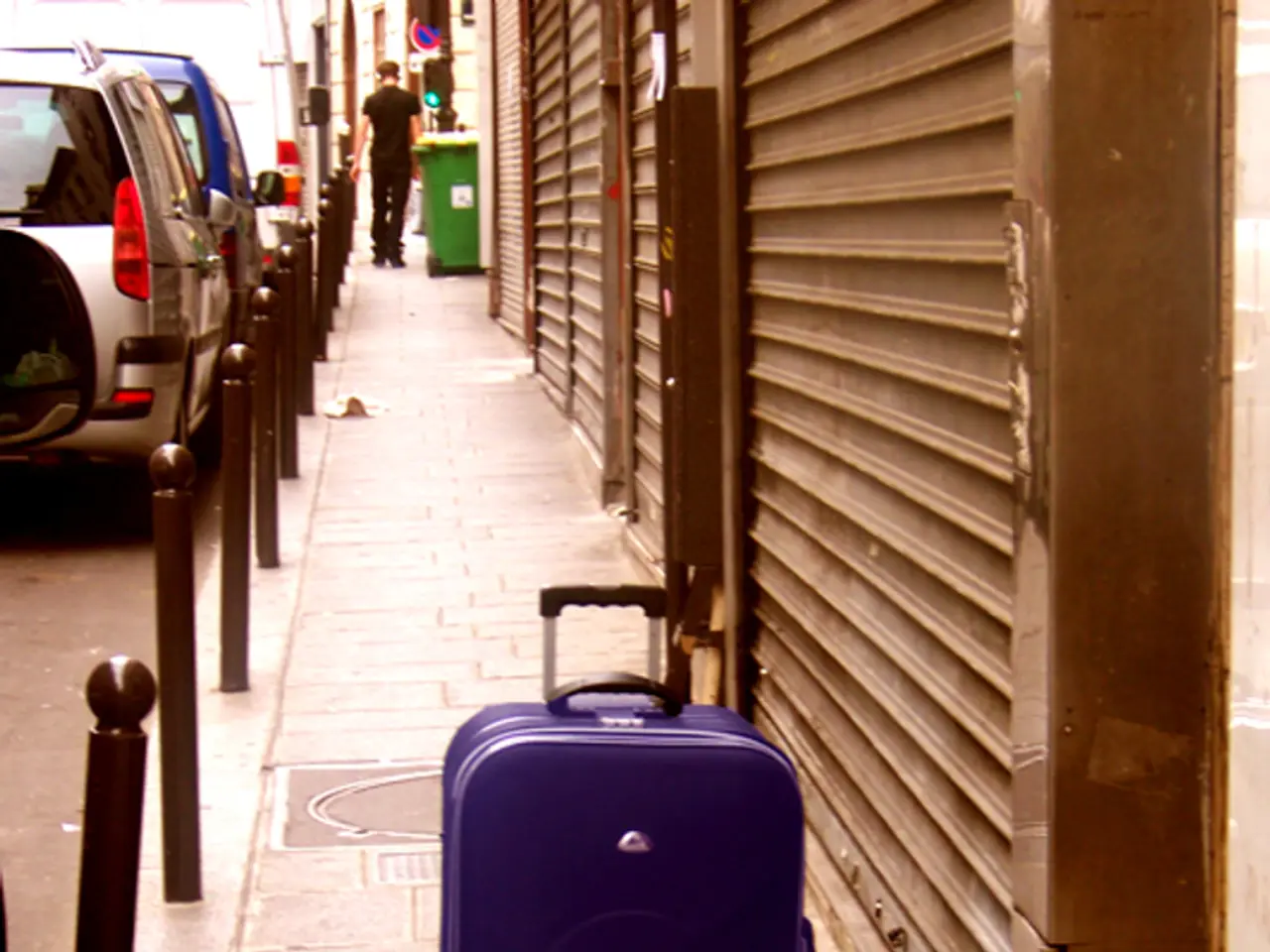 In this picture we can see a briefcase. There are cars on the road. Here we can see a man standing...