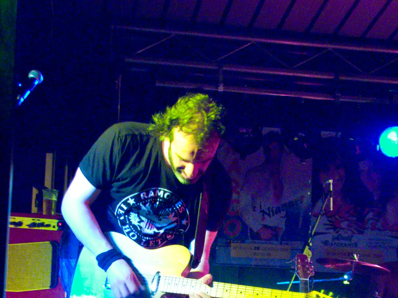 This is a picture of a man who is wearing a black shirt and holding a guitar and there is a black...