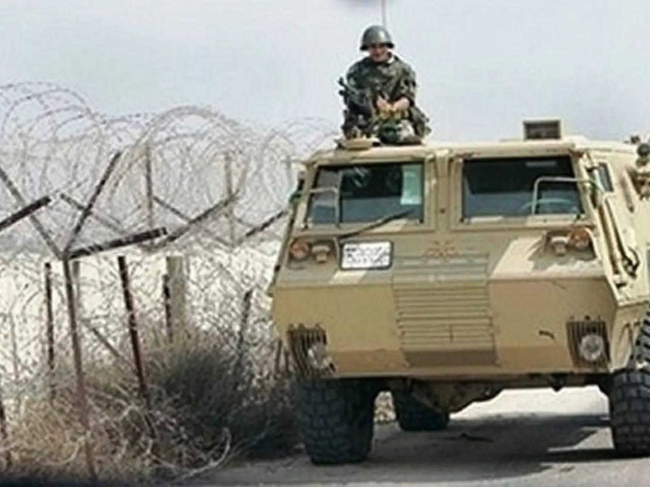 In this image there is a person in the vehicle. He is holding a gun. He is wearing a helmet. The...