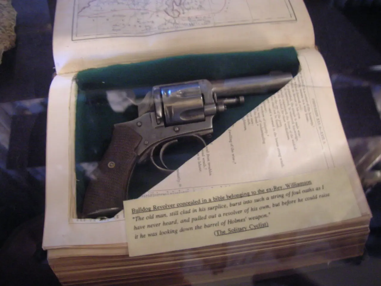 In this picture I can see a gun in the book and I can see text on the papers.