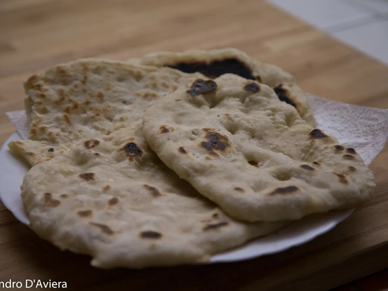 In this picture I can see food in the plate, on the table and they look like chapatis and I can see...