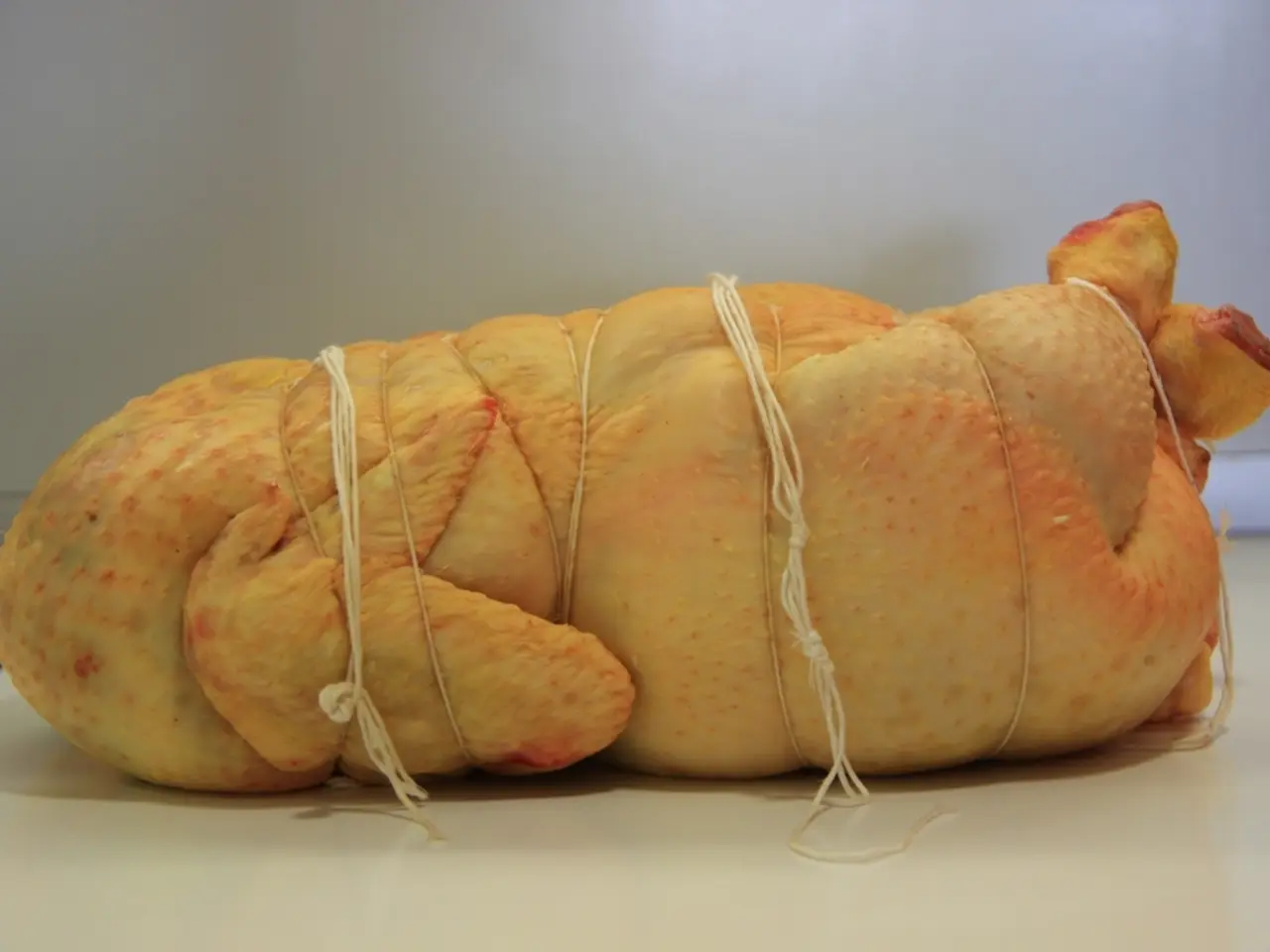 In this image I can see meat tied with the threads. There is a white background.