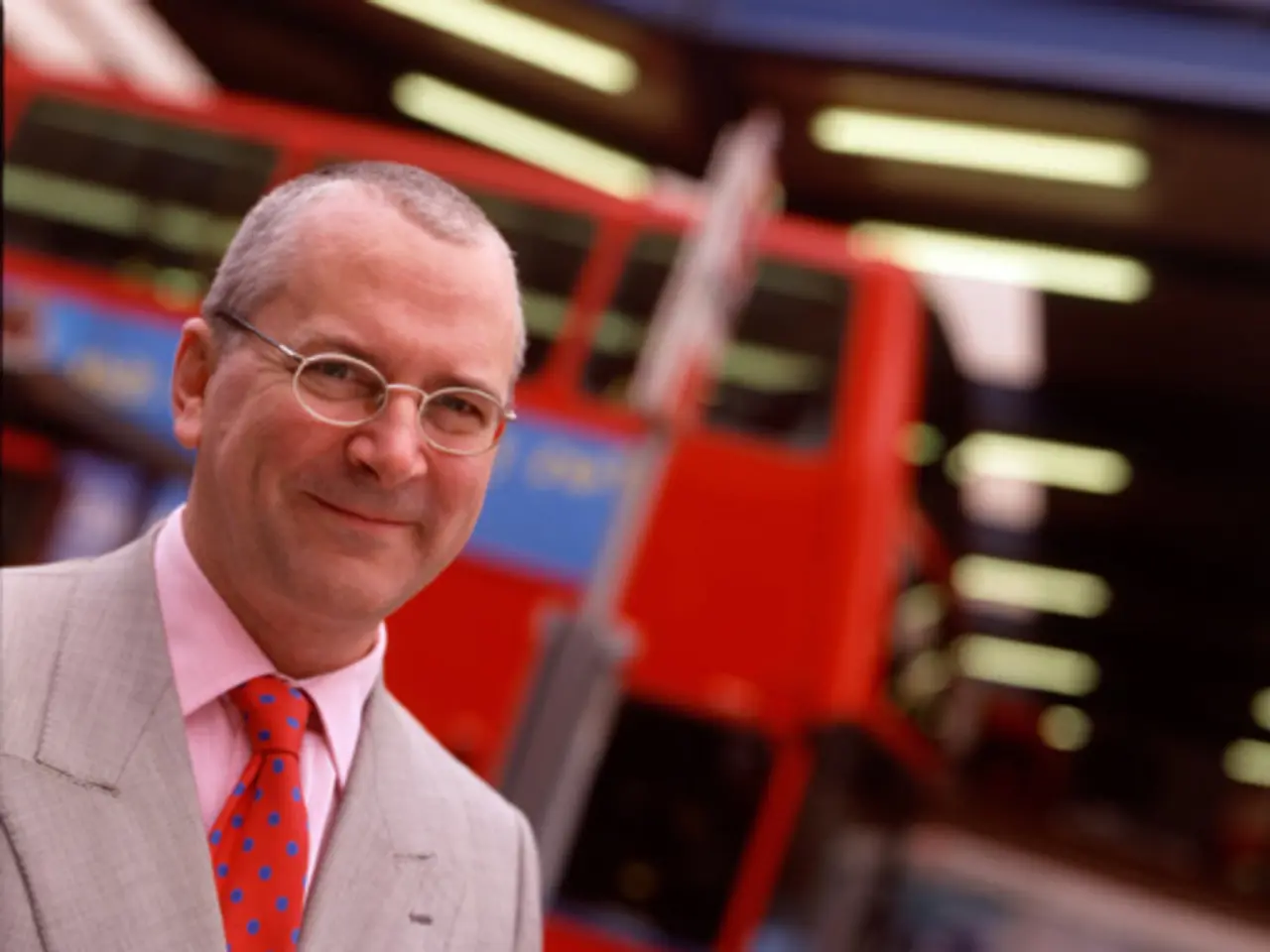 In this image we can see a man smiling. In the background there are electric lights, advertisements...