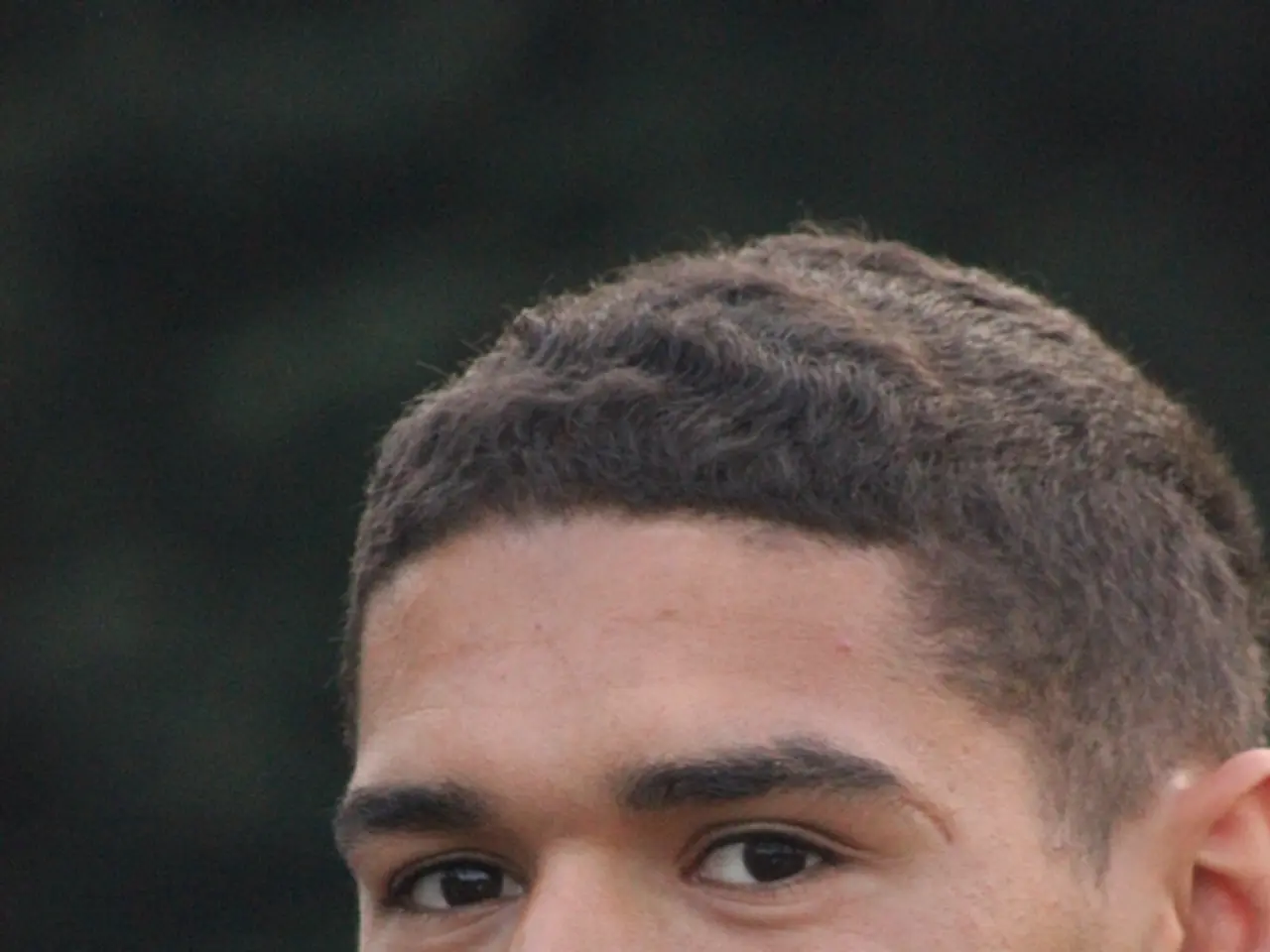 In the image there is a man smiling. Behind him there is a blur background.