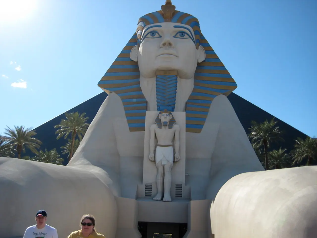 In the foreground of this image, there is an Egypt sculpture and there are two persons on the...