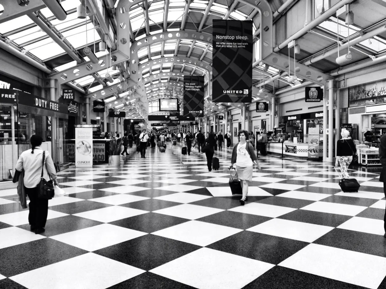 In this image I can see inside of the building in which some people are holding bags and walking,...