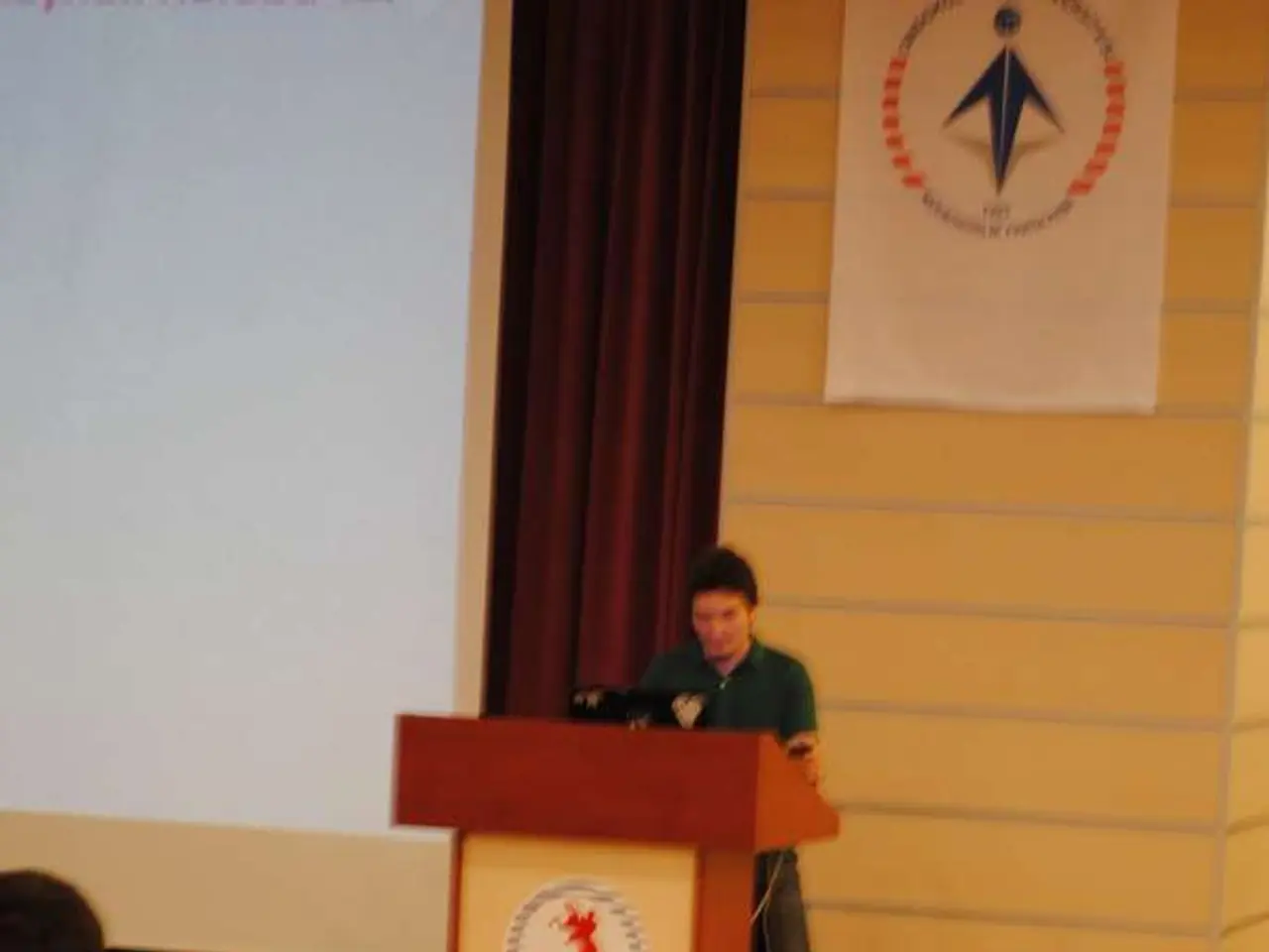 In this image in the center there is one person standing, in front of him there is a podium it...