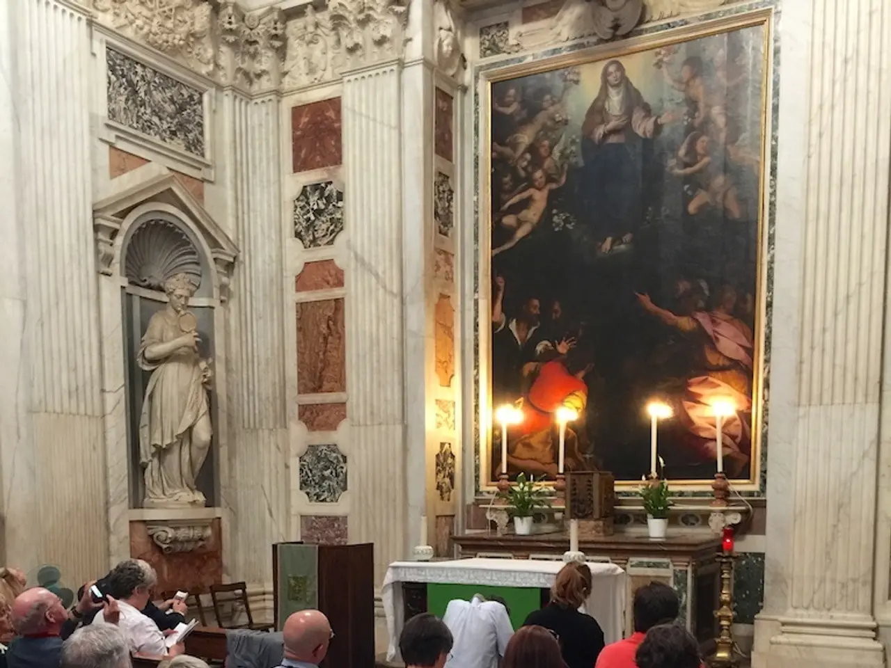 There is a group of people sitting on a chair and they are praying. Here we can see a photo frame...