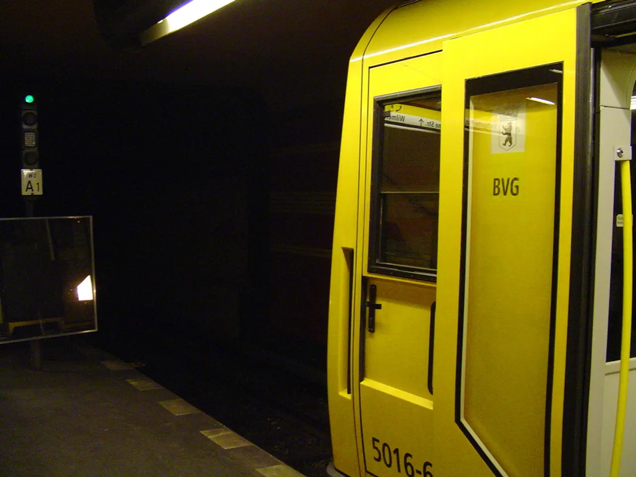 This is the picture of a railway station. On the right side of the image there is a train. On the...