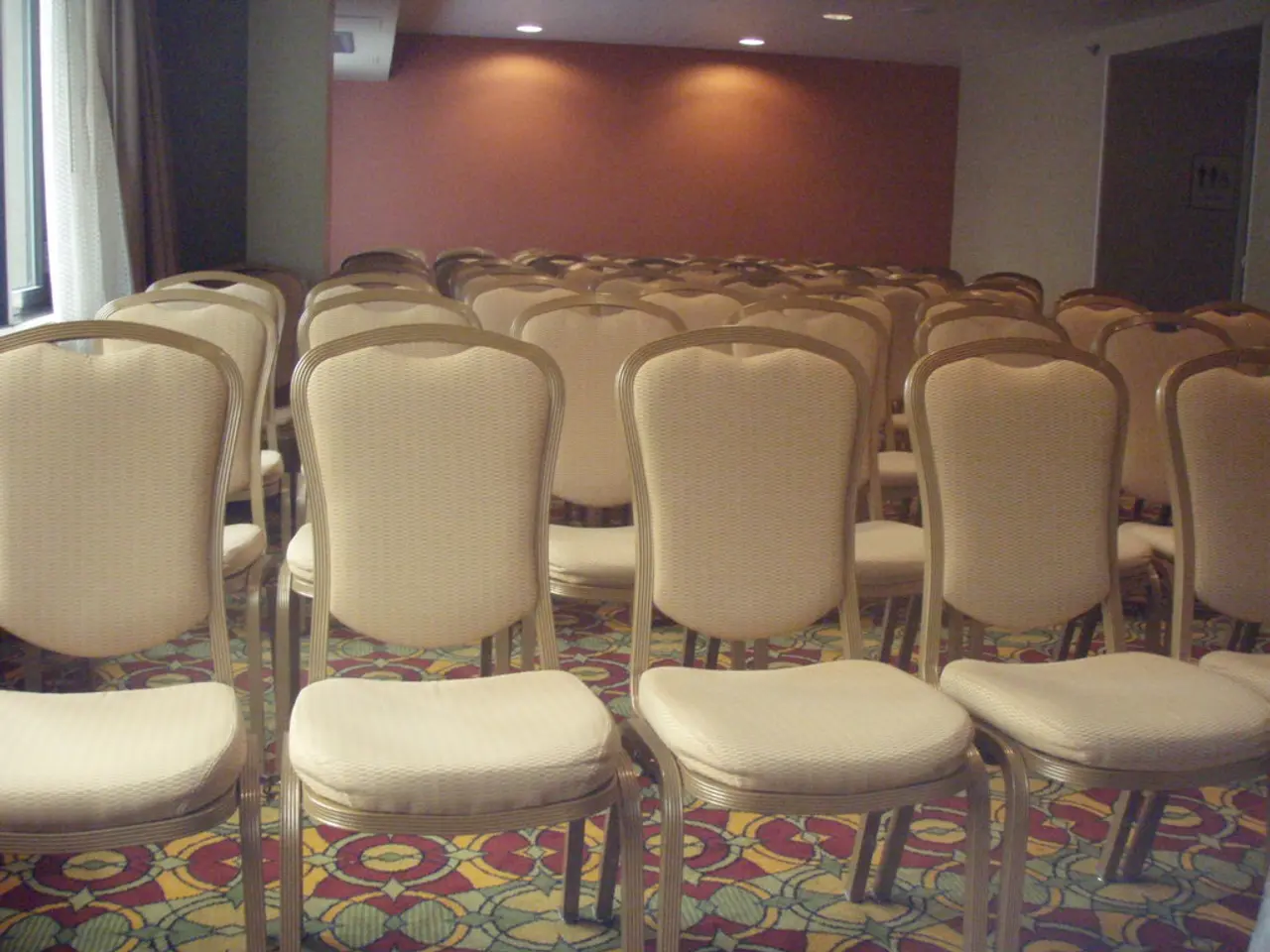 In a hall there are a lot of chairs arranged in an order,in the left side there is a window and in...