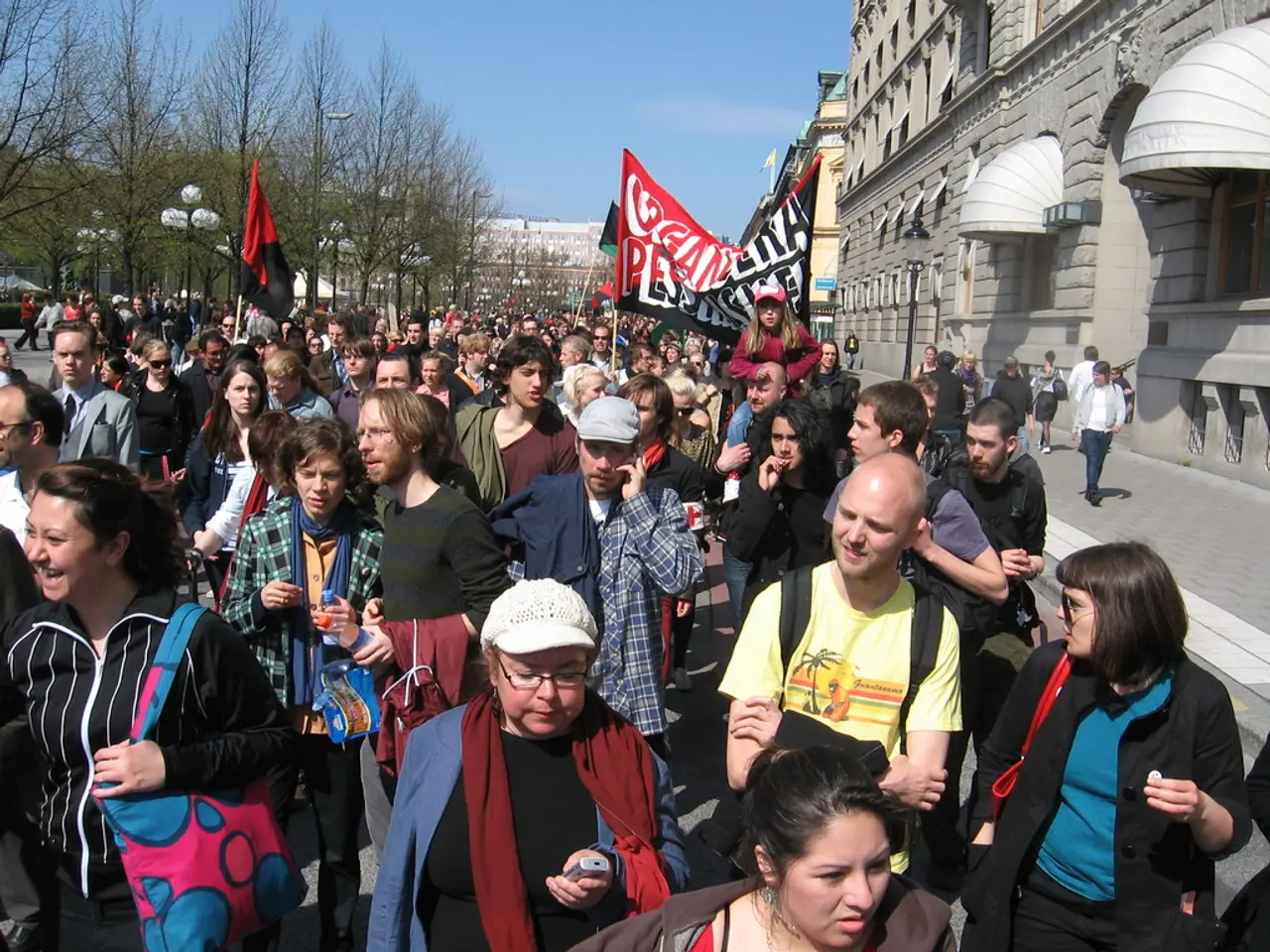 This picture is clicked outside the city. Here, we see many people walking on the road. The man in...